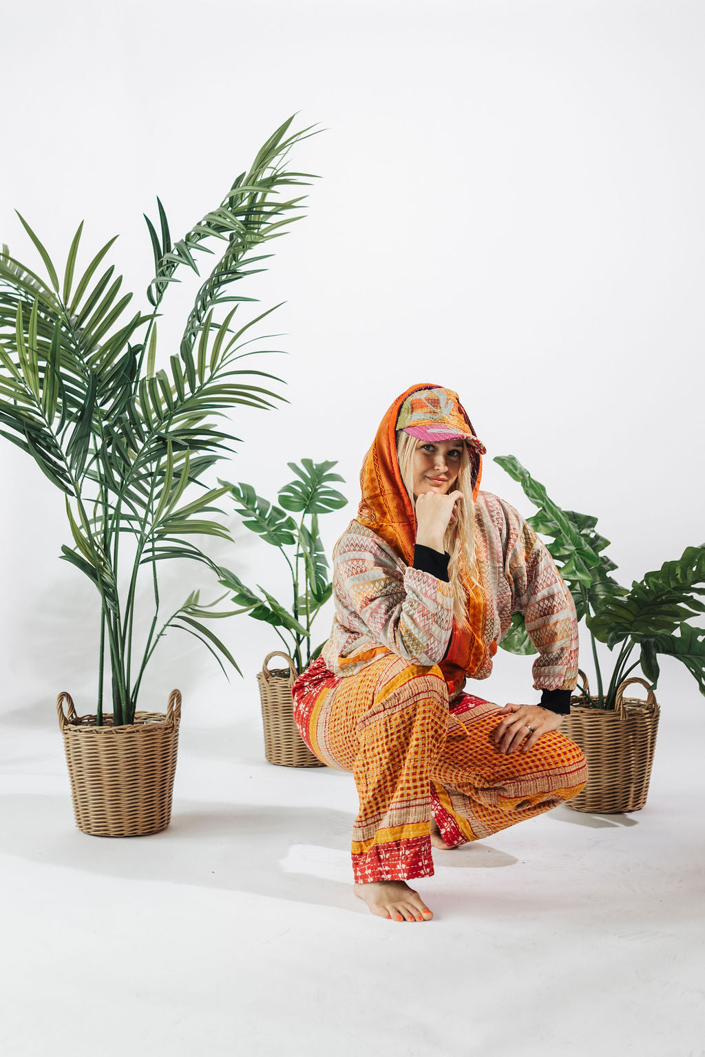 a woman in a colorful outfit squatting next to two baskets of plants