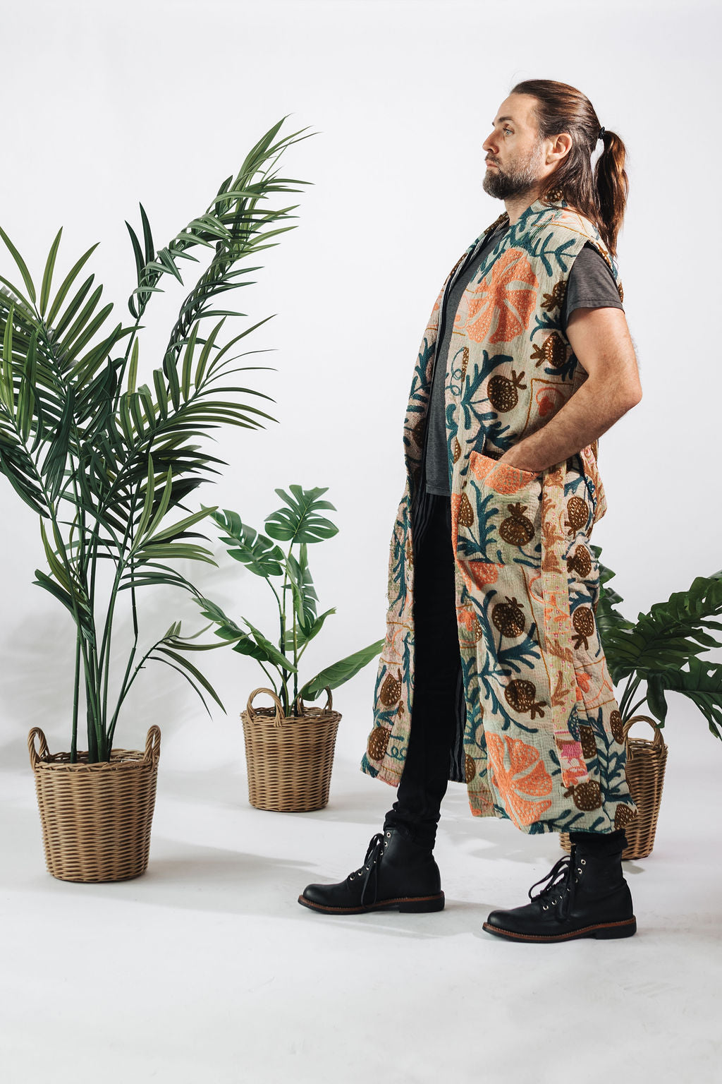 a man in a long vest and a plant