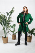 a man in a robe standing next to plants