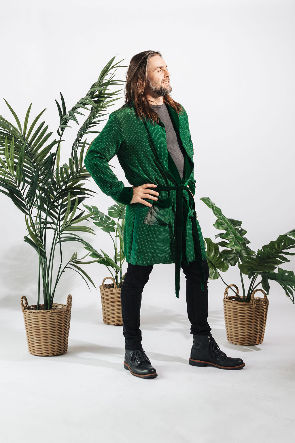 a man in a green robe standing next to plants