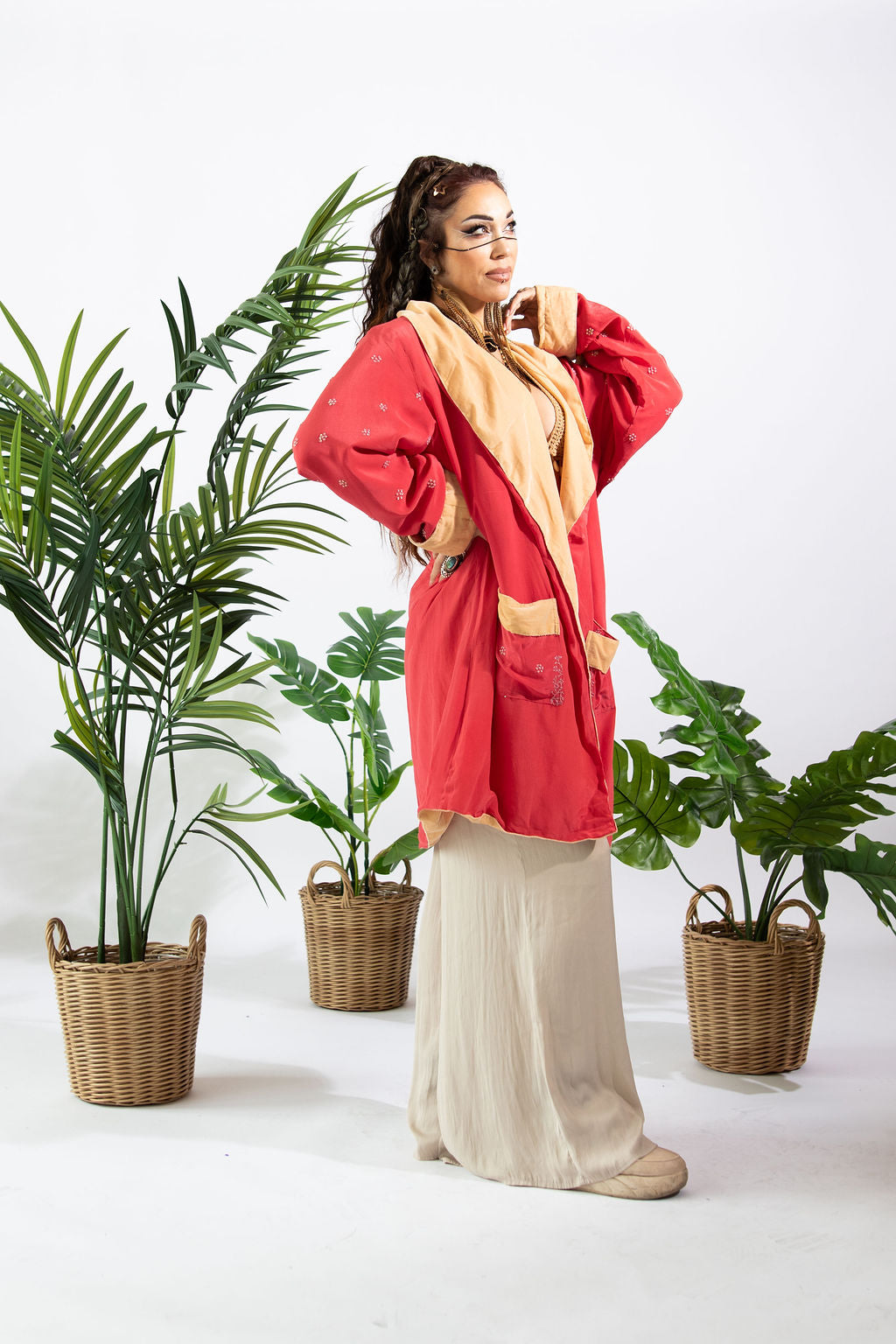 a woman in a red robe and white skirt standing next to plants