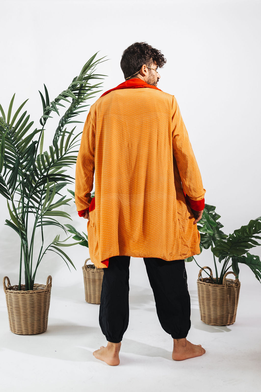 a man in an orange robe standing in front of two baskets of plants